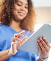 Health care worker smiles while using a tablet