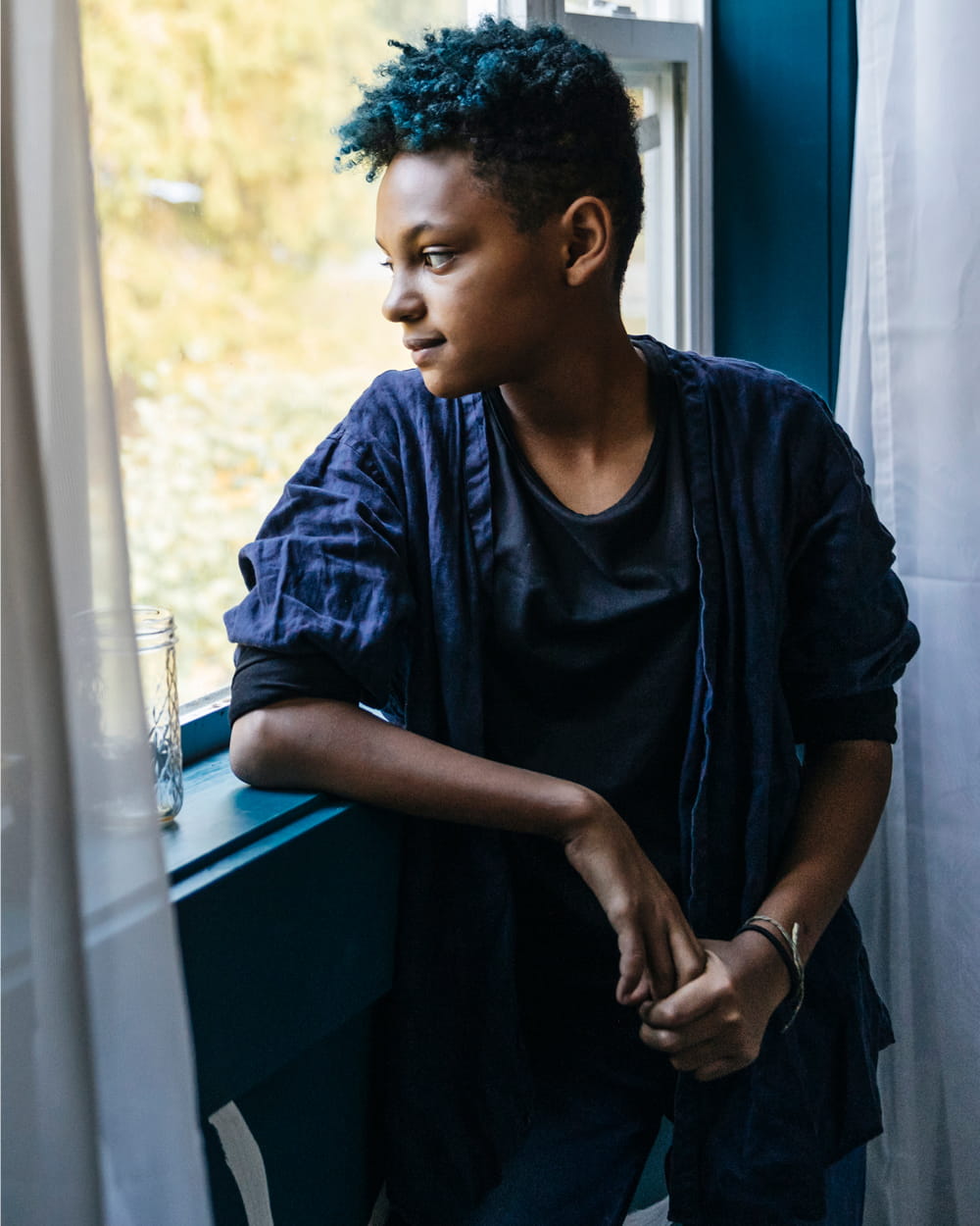 A young person looks out a window.