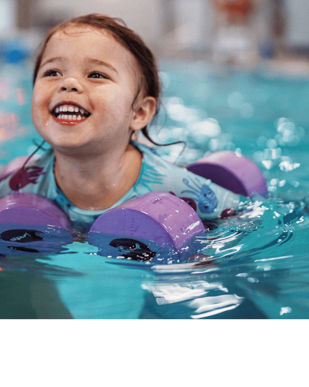 Woman helps child swim in pool.