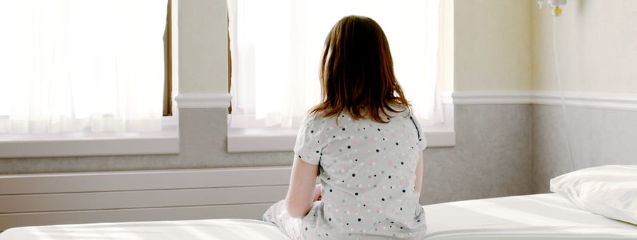 Child sitting on bed staring out window