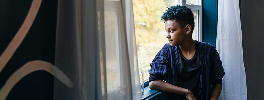 A young person looks out a window.