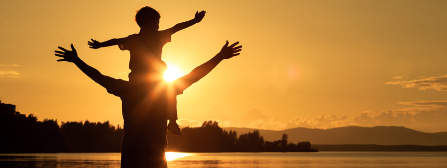 Parent and child look out over water at sunset.