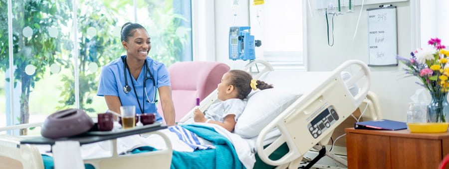 Nurse sitting at bedside of child patient.