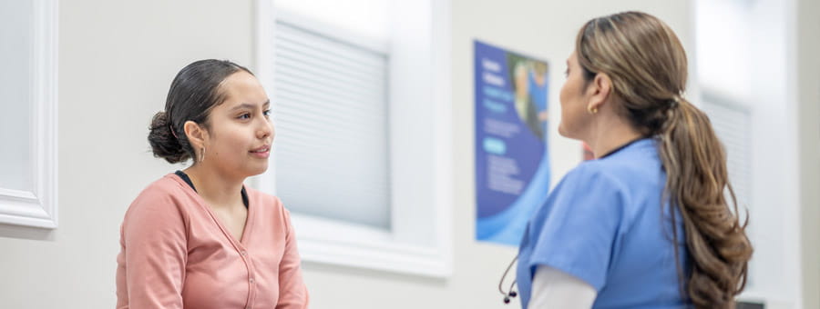 Teen and nurse talking in hospital setting.