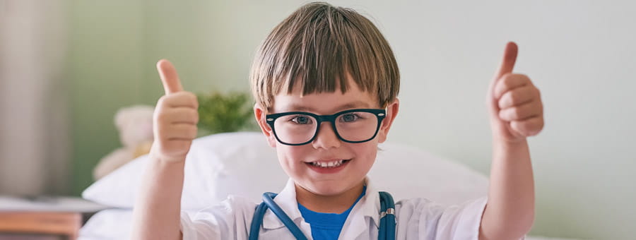 Happy young boy dressed up like a doctor giving double thumbs up.