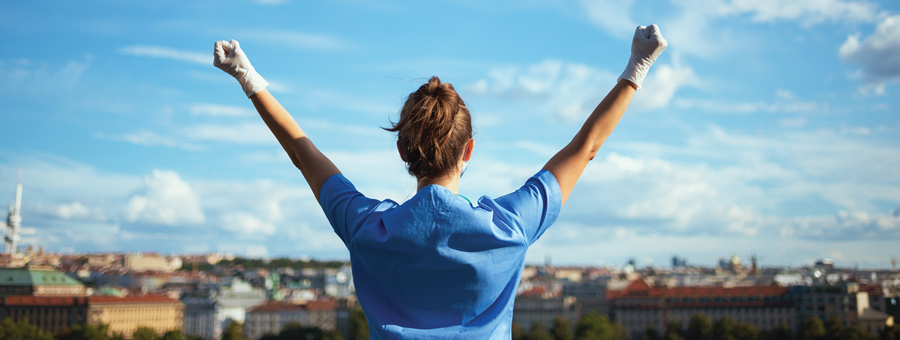 Medical professional with arms raised up to sky.