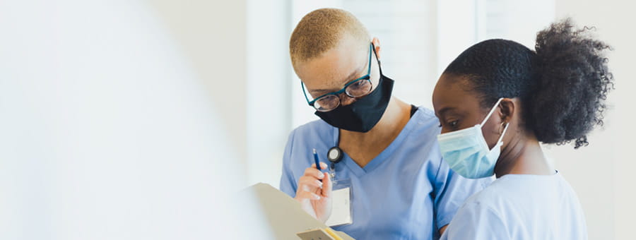Two nurses conferring in hospital hallway.