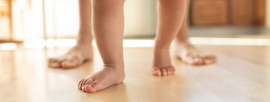 Baby and parent feet taking first steps.