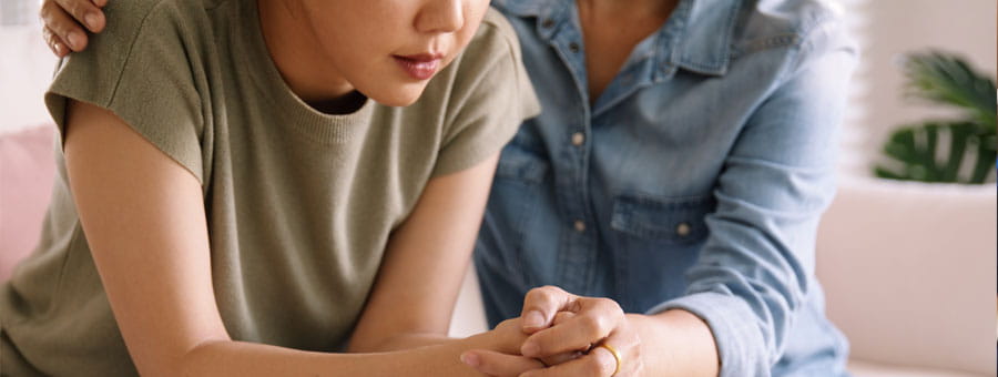 Mother comforting daughter, holding hand.