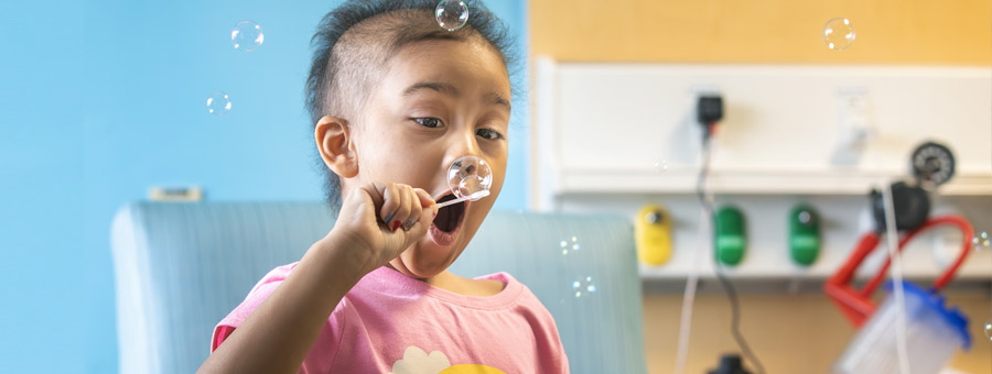 Child blowing bubbles in hospital room. Photo by Allyn DiVito.