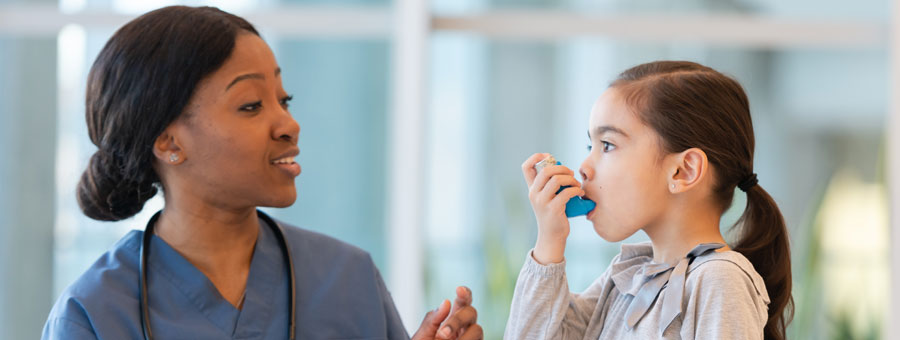 Respiratory therapist assists girl with inhaler.