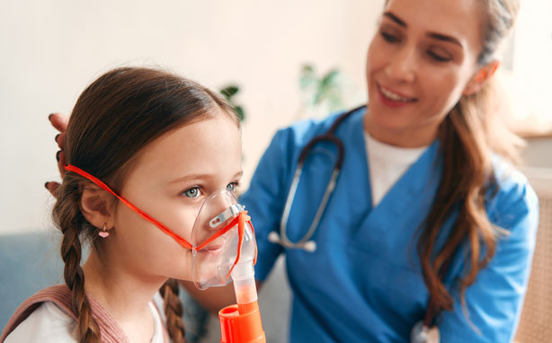 A respiratory therapist puts an inhalation mask on a child.