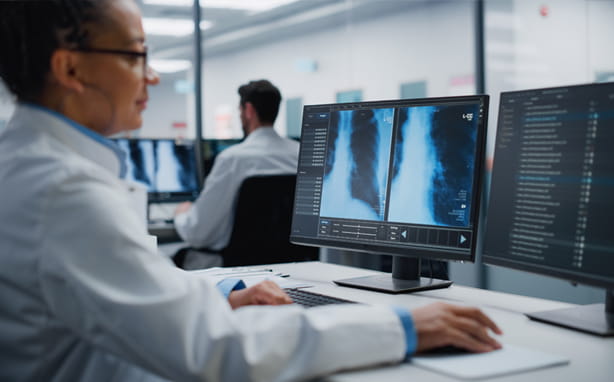 Doctor looking at scans and code on a computer.