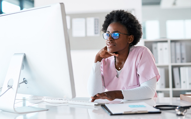 Nurse looking at schedule on desktop computer.