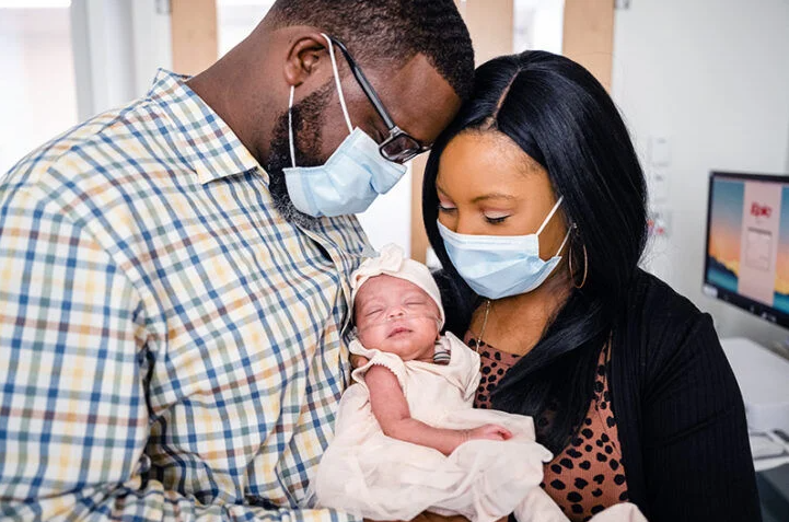 Two parents holding their infant child.