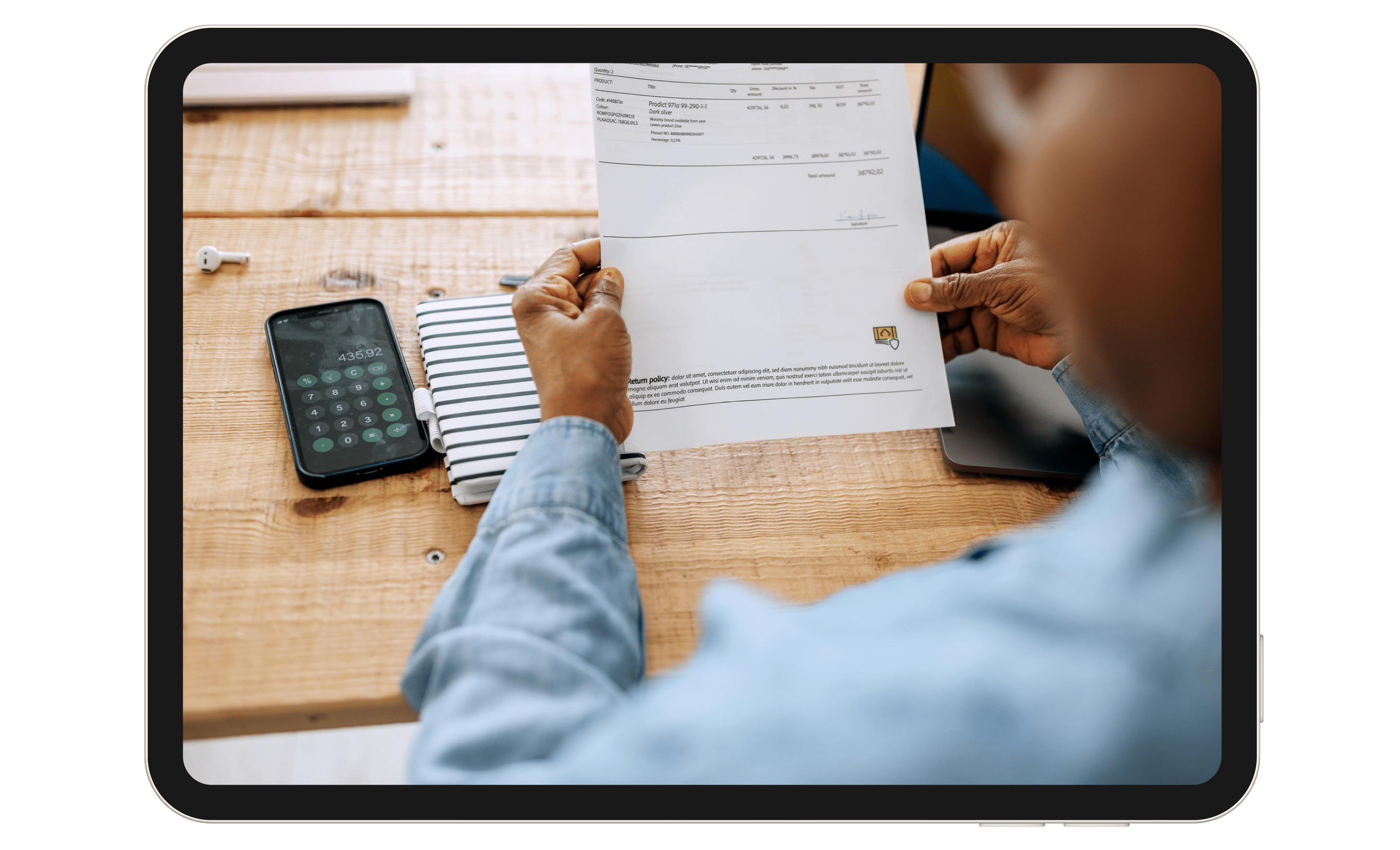 A person looking a piece of paper, with a calculator nearby.