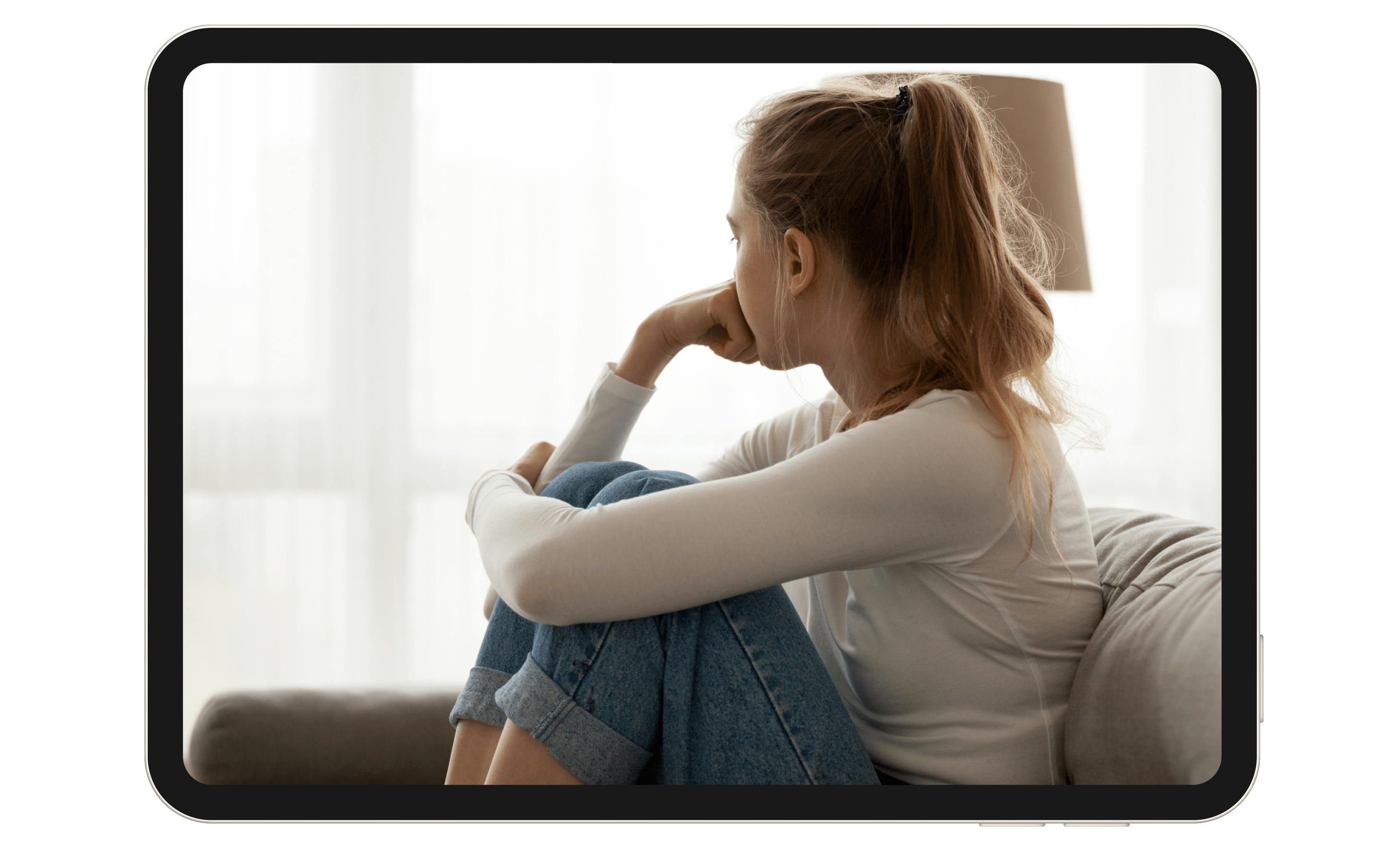 A young girl sitting on a couch, looking out the window.