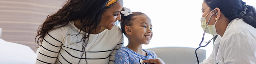 Mother sits with her daughter while she is examined by doctor.