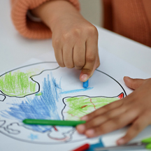 Child hands coloring in drawing of Earth.
