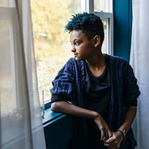 A young person looks out a window.