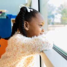 A young girl looks out a window.
