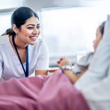 Nurse talking with child patient in hospital bed.