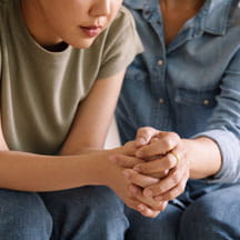 Mother comforting daughter, holding hand.