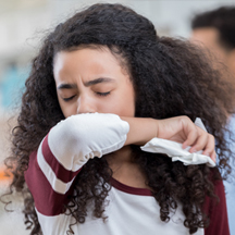 Young girl coughing in classroom.
